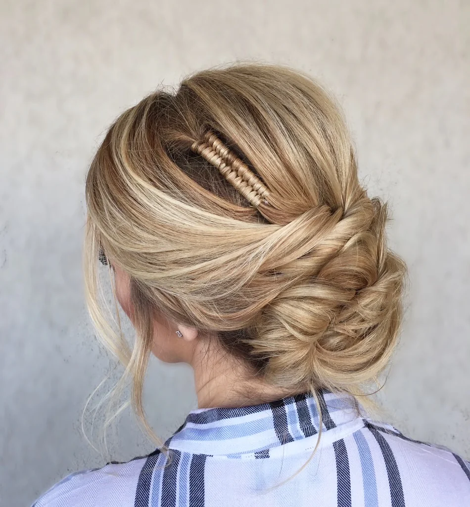 Blonde hair swept into an intricate textured updo with a woven accent