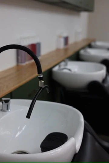 White ceramic shampoo bowls and black spray hose inside Muse Beauty Bar